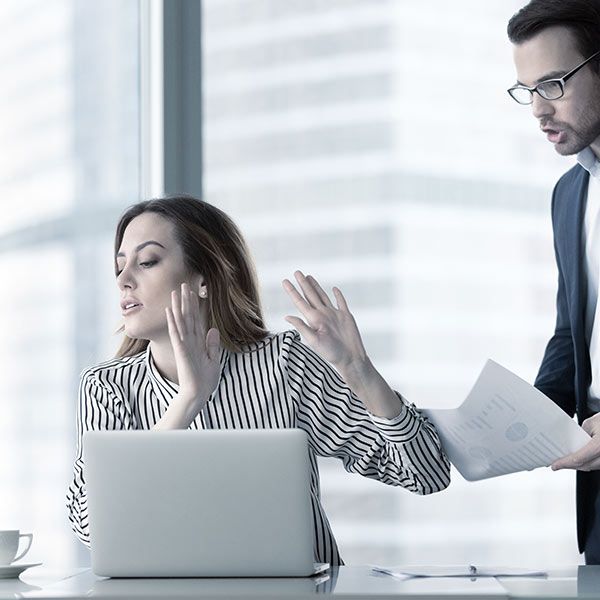 Woman holding up hands to male coworker
